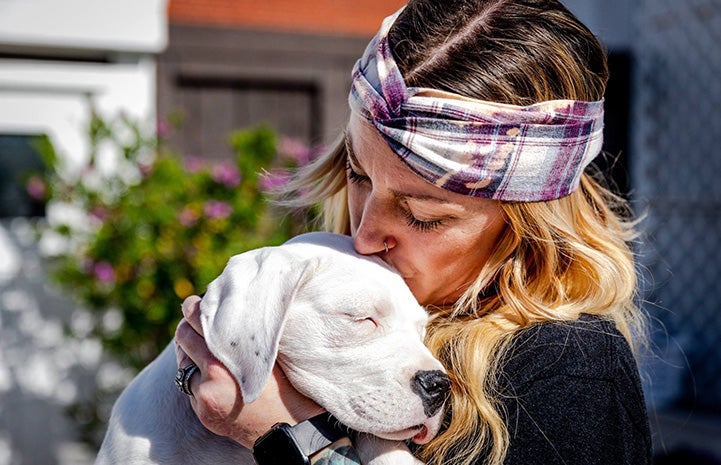 Woman holding Clover the puppy and giving her a kiss on her head