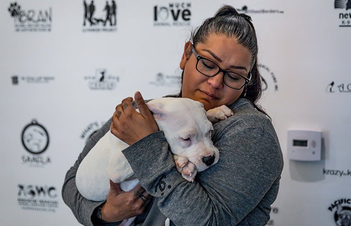 Woman cradling Clover the puppy in front of a backdrop