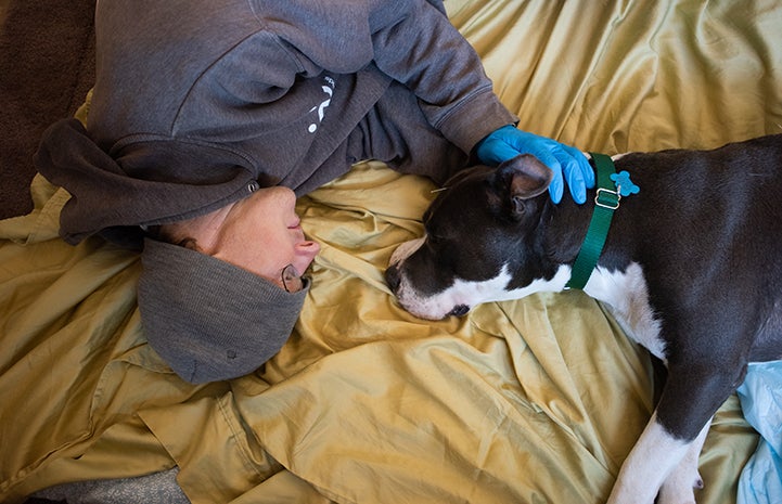 Caregiver Paul lying on the floor on a blanket next to Audrey the dog