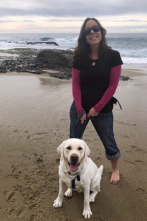 Cosmic Charlie the dog and a woman out on a walk on a beach