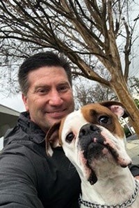 Roscoe and his adopter, outside under some trees without leaves