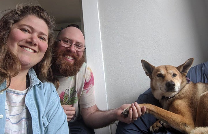 Elizabeth and Jay next to Brownie the dog and holding one of her paws