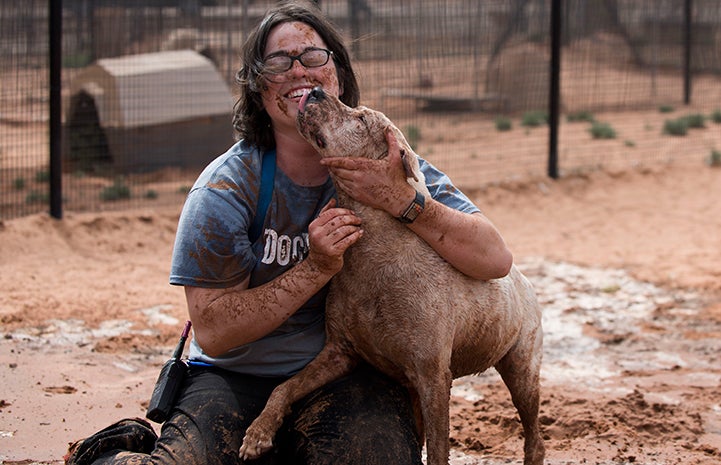 Caregive Haylee huggin Yuma the dog, both very muddy