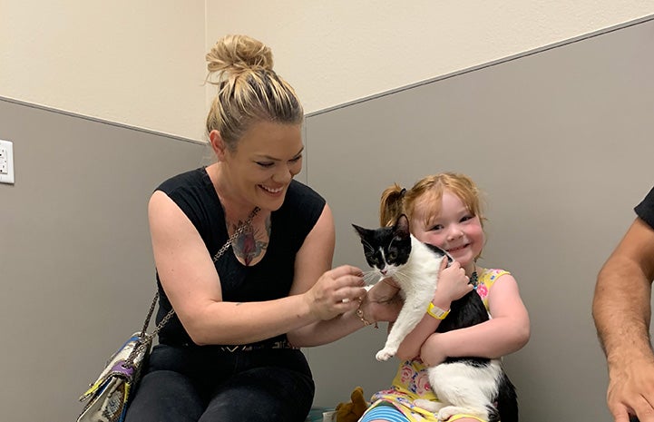 Smiling woman and toddler holding a black and white cat