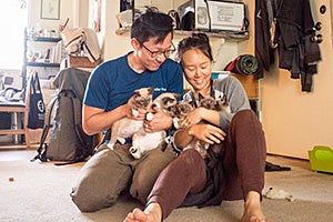 Yomi and David Soobin Lee smiling and sitting on the floor holding foster kittens