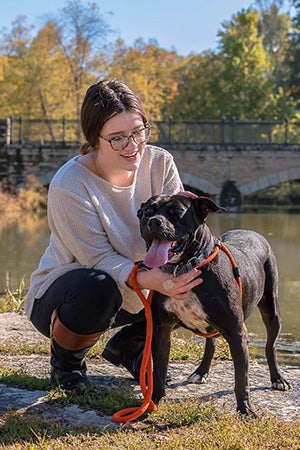 Jellybean the dog out on a walk outside in front of a river and bridge