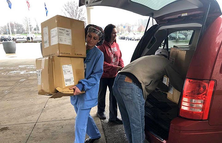 People unloading boxes of personal protective equipment (PPE) from a vehicle