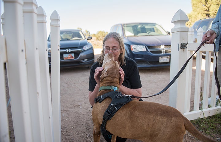 Caroline Lynch bending down to give a hug to DoSiDo the dog