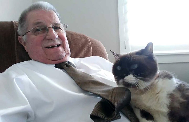 BJ sitting in a chair with Valerie the Siamese cat sitting on his lap