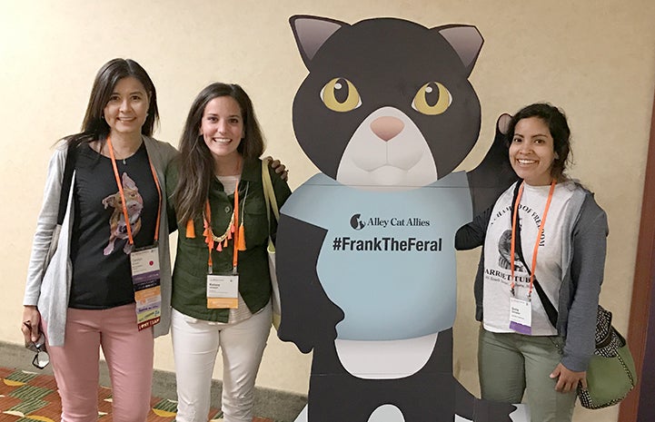 Three women posting next to Alley Cat Allies Frank the Feral cardboard figure