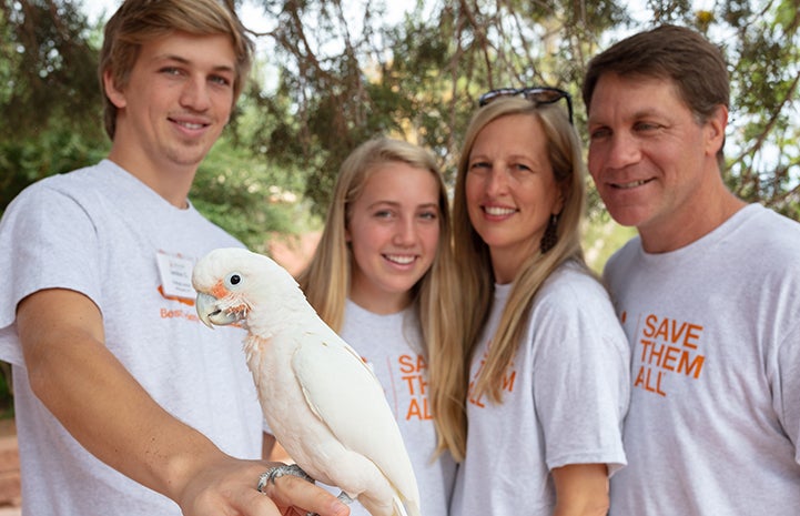 Matt, Loulie, Landon and Berkeley Scharf smiling and holding a parrot