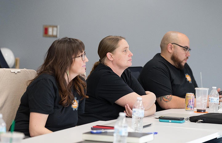 Sarah Hock and two other people sitting at a desk listening in class