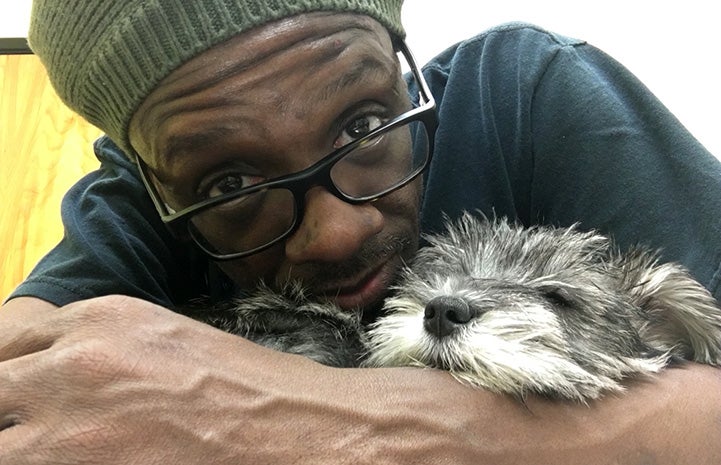 Johnny Jankins snuggling with a small fluffy gray and white dog