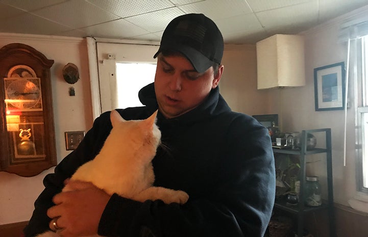 Bentley the white cat being held by his dad