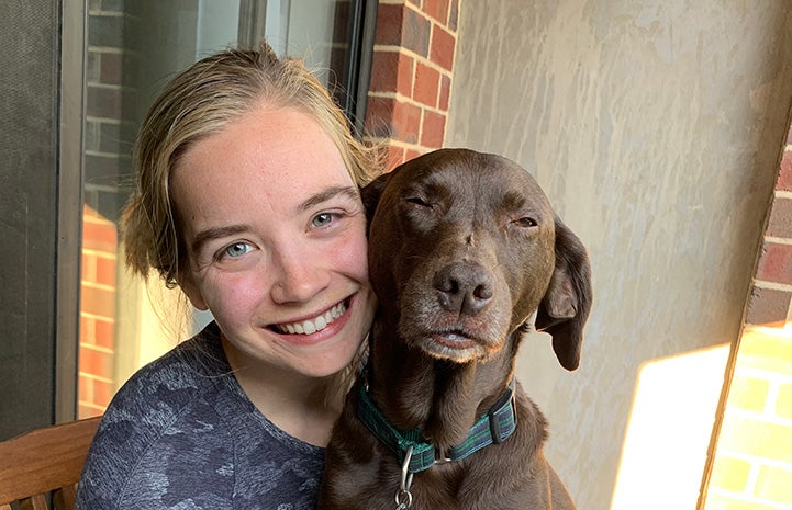 Carl the dog face-to-face next to the woman who adopted him