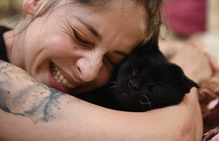 Jade Campbell smiling and hugging Duke the cat and both have their eyes closed in bliss