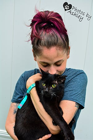 Jade Campbell holding Duke the cat with her arms wrapped around him in a hug