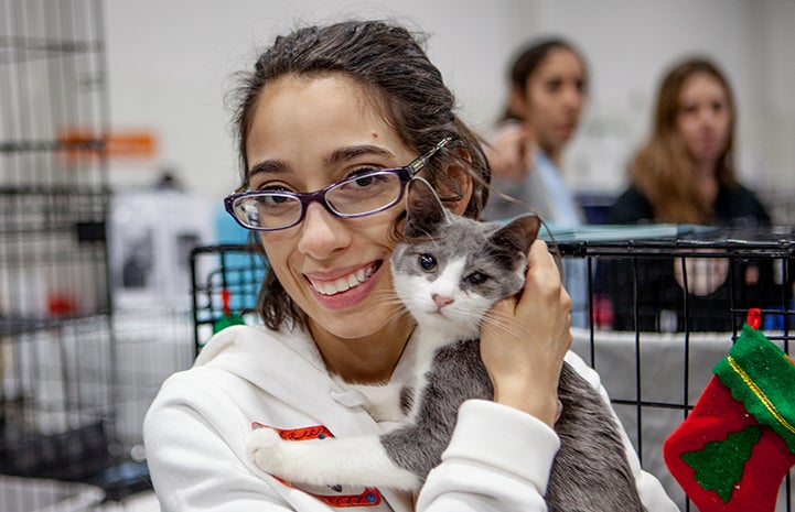 Smiling woman holding a gray and white cat