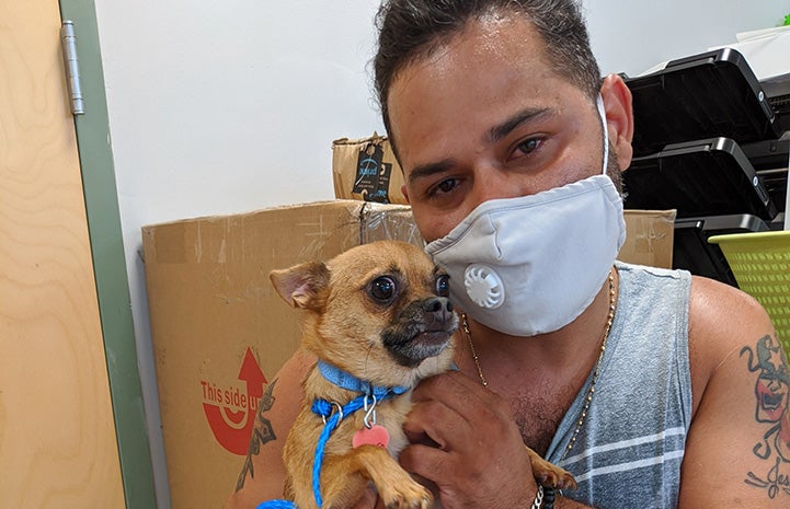 Masked man holding Chubbs the dog