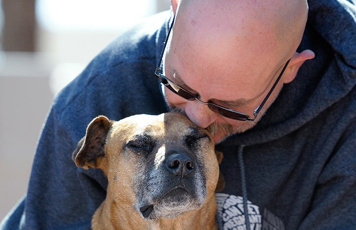 Kevin kissing the top of the head of Vicktory dog Layla