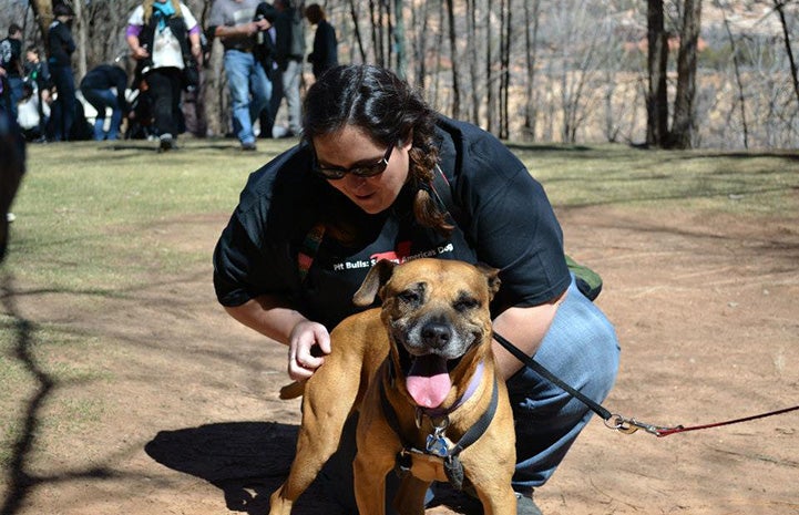 Woman squatting down to pet Layla the Vicktory dog at Angels Landing