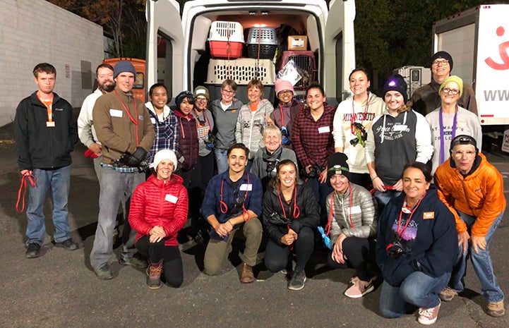 Group of people standing in front of the back of a transport van