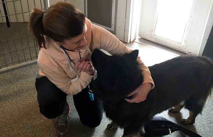 Maryann hugging Donner the dog inside a run at the sanctuary