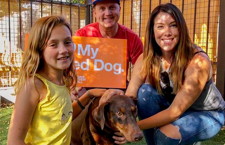 Hannah the doberman with the Kocicka family holding a sign