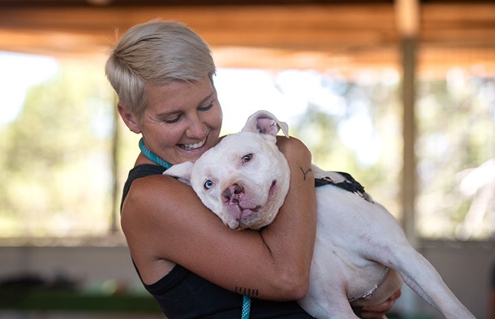 Woman caregiver Amie giving a hug to Ludwig the dog