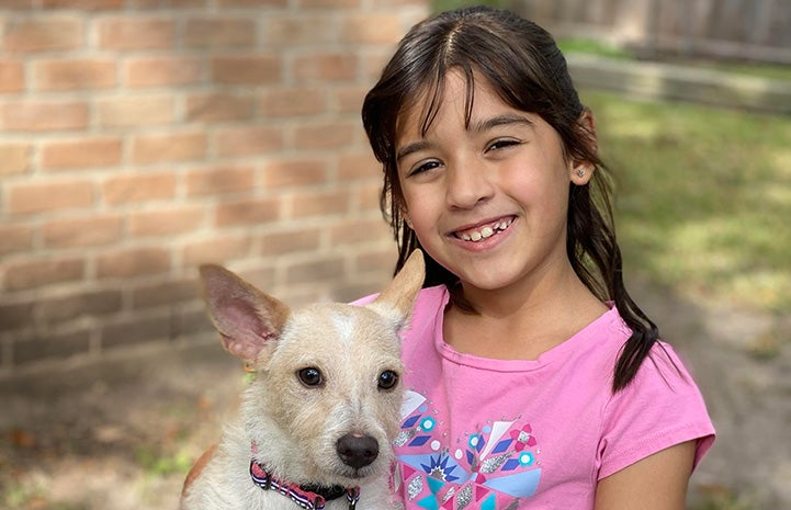 Young girl wearing a pink shirt holding Trudy the dog