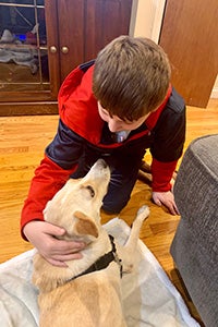 Kash the dog looking up at JP, a young boy wearing a red and black jacket