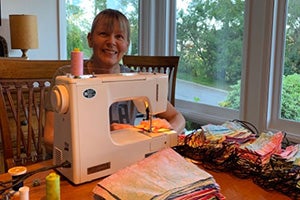 Volunteer Gilly sitting at a sewing machine making masks