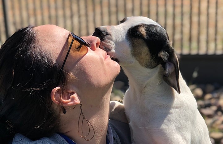 Kendall McGhee getting a kiss from a puppy while volunteering at Best Friends