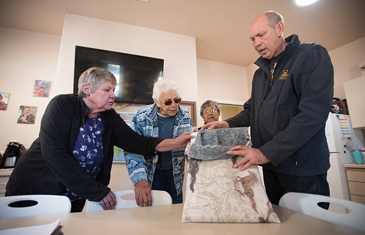 Two women and a man looking at a rabbit blanket