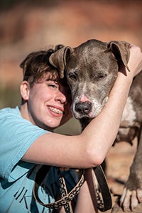 Young girl hugging a fawn and white dog