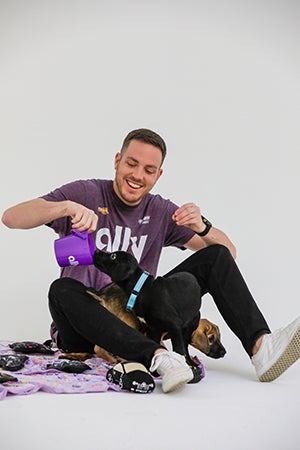 Alex Bowman wearing an Ally T-shirt playing with two puppies