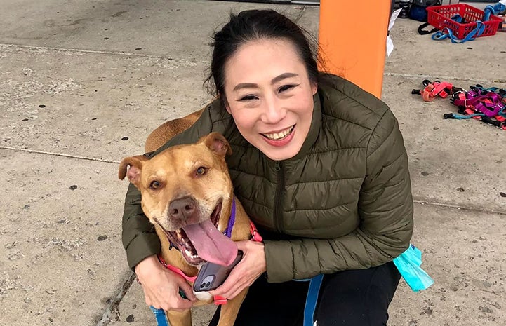 Smiling person next to dog whose mouth is also open in a smile, with tongue out