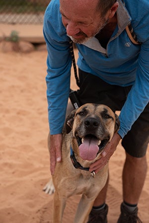 Caregiver Matt Fisher reaching down to pet Southeast the dog