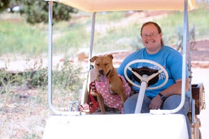 Fiesta the shy dog in her spotted pink dress and Alyssa riding in a golf cart