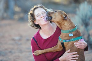 Former fighting dog Pretty Girl giving a woman a kiss