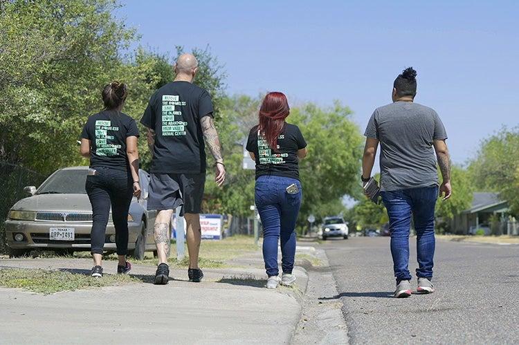 The backs of four people as they are advocating for animals in a neighborhood