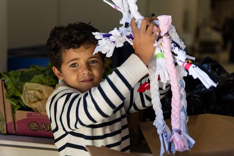 Young boy holding bunch of homemade braided rope toys for dogs