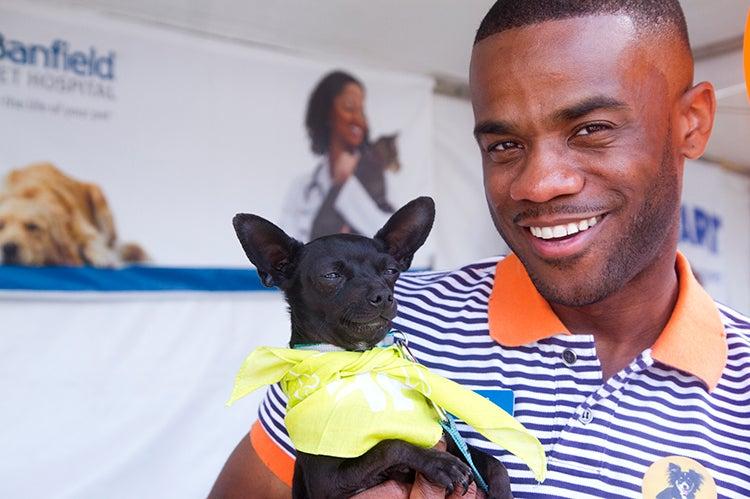 Smiling person who adopted a small black dog wearing a yellow bandana