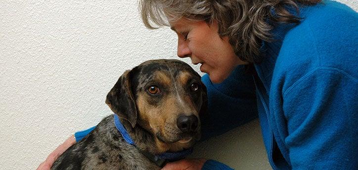 Woman reassuring her dog who is scared of thunderstorms