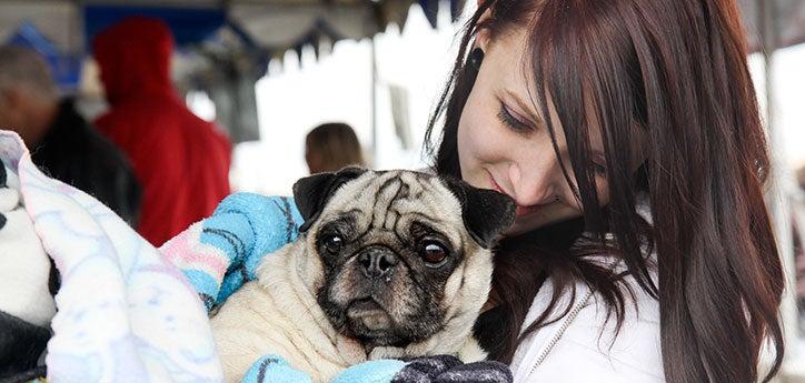 person, who is receiving some pet financial assistance during a difficult time in her life, with her pug