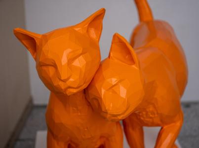 Orange statue of two cats affectionately rubbing against each other