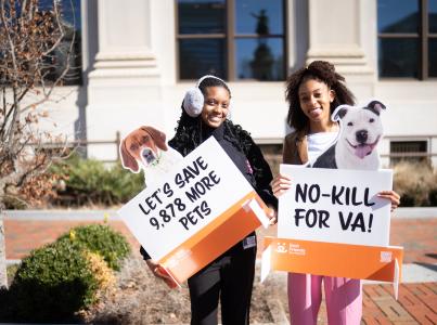 Two people holding signs outside at the Virginia no-kill event