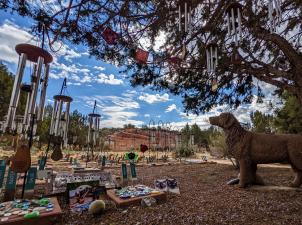 Angels Rest with markers, windchimes, a statue, and prayer flags in a tree