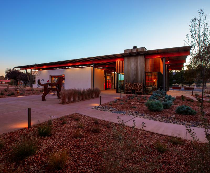 Exterior photo of the sun setting behind a modern building in the desert