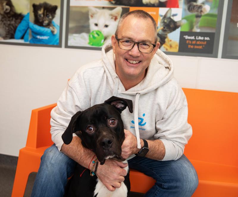 Smiling person sitting on a bench with a dog 